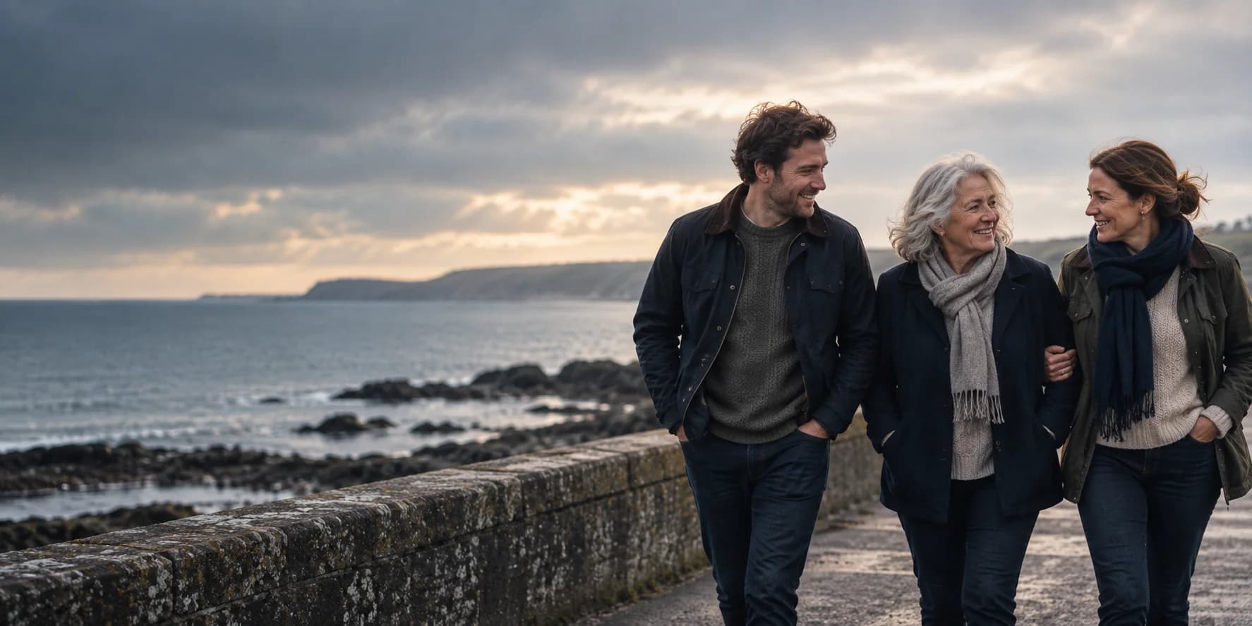 Three adult family members walking together beside the coast